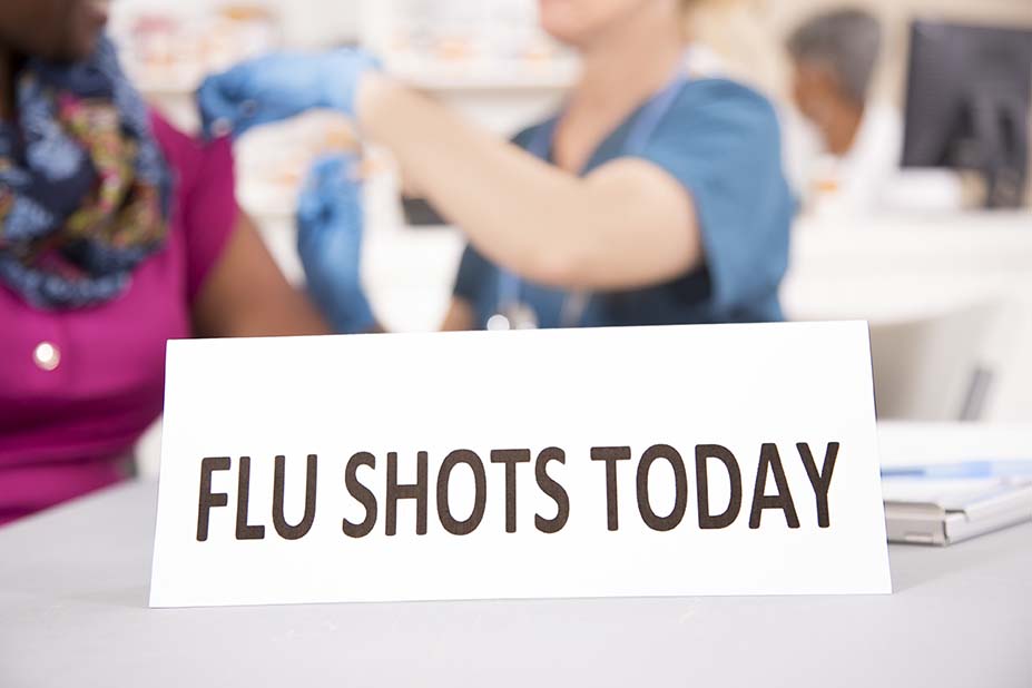 Nurse gives flu shot vaccine to patient at pharmacy.